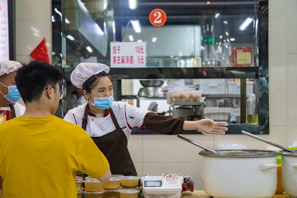 介绍自家的粥品（学通社记者 徐剑锋 摄）